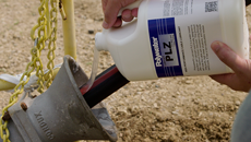 Man pouring a white 1-gallon jug of Polywater PLZ cable lubricant on an electrical cable in a conduit